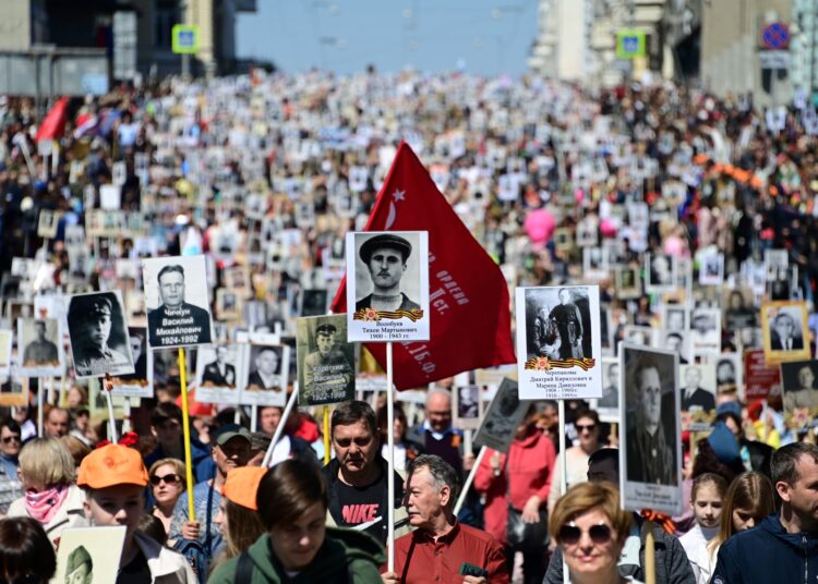 People carry portraits of their relatives - WWII soldiers - as they take part in the Immortal Regiment march in the far eastern city of Vladivostok on May 9, 2022. - Russia celebrates the 77th anniversary of the victory over Nazi Germany. (Photo by Pavel KOROLYOV / AFP)