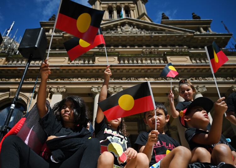 Youths and children wave the Australian aboriginal flag as protesters take part in an "Invasion Day" demonstration on Australia Day in Sydney on January 26, 2022. (Photo by Steven Saphore / AFP)