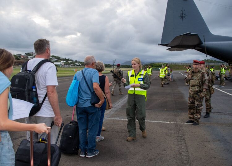 This handout photo taken on May 21, 2024 and released on May 22 by the New Zealand Defence Force shows members of the Royal New Zealand Air Force, along with other military personnel, preparing to assist people being evacuated at Noumea-Magenta Airport in Noumea. - The Royal New Zealand Air Force C-130 aircraft used to evacuate tourists trapped in riot-hit New Caledonia landed in New Zealand on May 21, the first rescue flight for New Zealanders since looting, arson and deadly gunfire enveloped the French Pacific territory eight days ago. (Photo by Handout / NEW ZEALAND DEFENCE FORCE / AFP) / RESTRICTED TO EDITORIAL USE - MANDATORY CREDIT "AFP PHOTO / NEW ZEALAND DEFENCE FORCE" - NO MARKETING NO ADVERTISING CAMPAIGNS - DISTRIBUTED AS A SERVICE TO CLIENTS