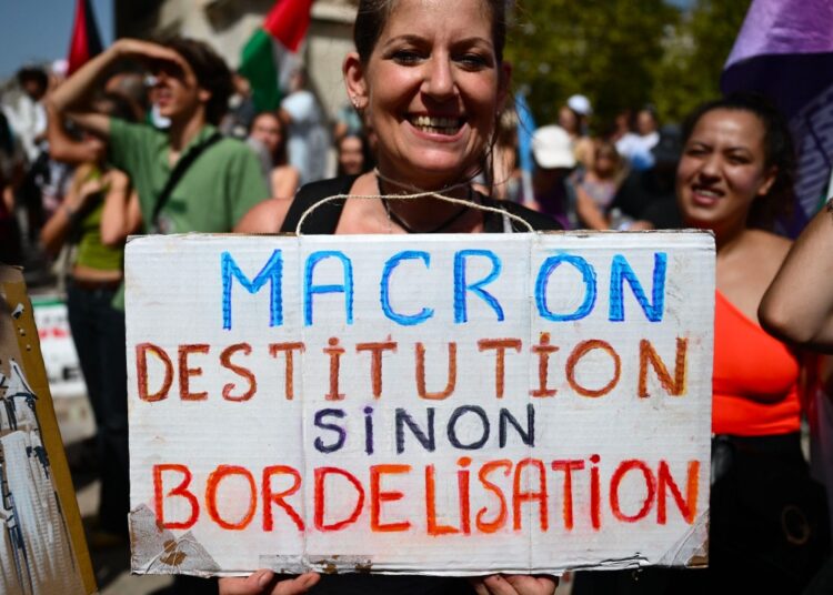 A demonstrator holds placard reading in French "Macron destitution or disorder" take part in a demonstration against the appointment of right-wing Prime Minister Michel Barnier by France's President Emmanuel Macron in Marseille, southern France, on September 7, 2024. - Nationwide protests are taking place on September 7, led by political leaders from France's left-wing coalition of parties, together with labour unions, to denounce France President for not appointing a left-wing prime minister after he took the risk of dissolving parliament in June, and calling a July snap elections in which his centrist alliance lost its relative majority in parliament. (Photo by Christophe SIMON / AFP)